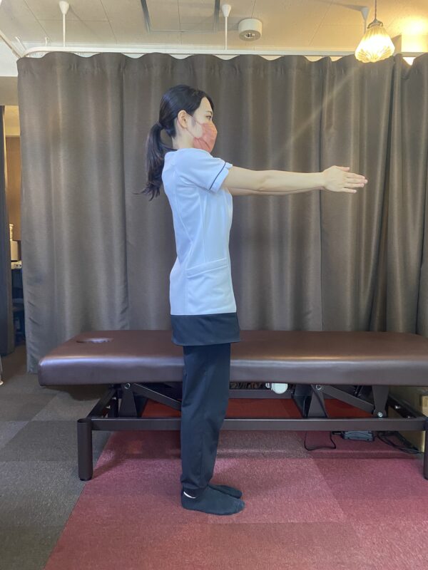 立った姿勢で両手を前に合わせ、腕を伸ばす背中のストレッチ